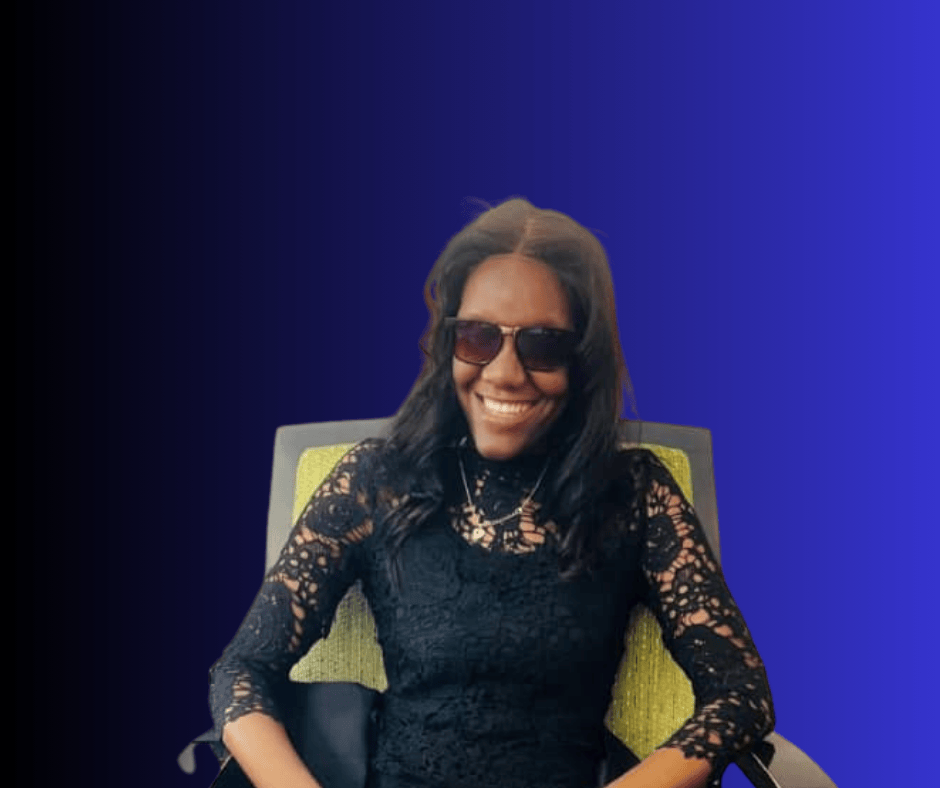 image of Hilia Angula wearing a black lace dress, dark shades and sitting on an arm chair